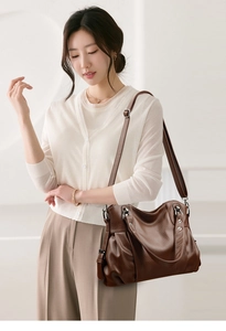 Detail of brown leather handbag featuring pleated design and wide adjustable strap
