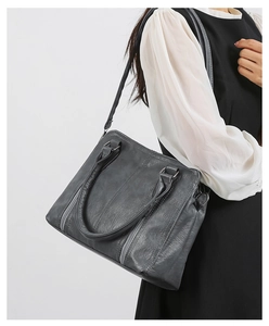 Detailed view of grey textured leather shoulder bag with vintage zipper and stitching details