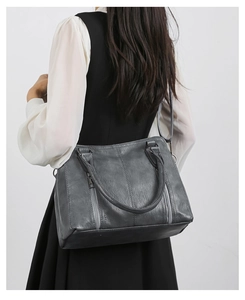 Detail shot of dark gray shoulder bag featuring vertical metal zippers and matte PU leather