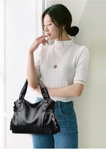 Close-up of black lychee grain leather tote bag with silver metal ring and decorative zipper
