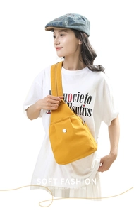 Detailed view of lightweight yellow nylon crossbody bag featuring a round metallic logo