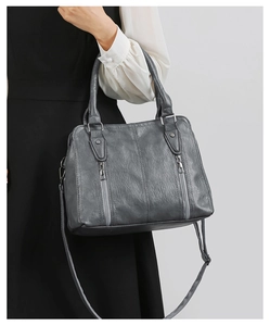 Detail of dark grey litchi grain leather bag with dual vertical zippers and sturdy handles