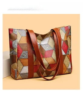 Detail of color-block tote bag with crocodile and snakeskin textures and brown straps