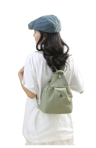 Detail of light green nylon mini backpack with front pleated pocket and round logo