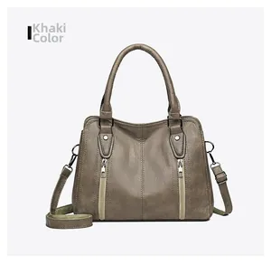 Detail view of khaki faux leather handbag featuring litchi texture and dual zippers