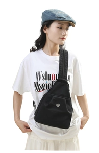 Detail of adjustable strap and round metal logo on durable black nylon crossbody bag