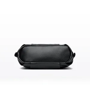Detail view of the wide flat bottom on a black litchi grain leather handbag