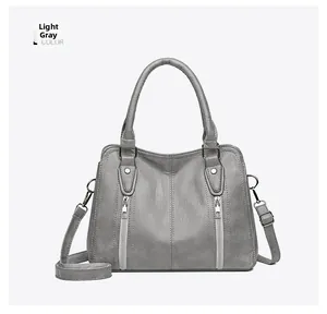 Detail of light gray crossbody bag showing lychee pattern faux leather and side zippers