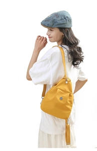 Detailed side view of bright yellow lightweight nylon chest bag on model's back