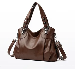 Detail view of large brown tote bag showing textured leather and adjustable shoulder strap