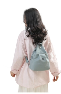 Rear view of a model wearing the light grey-blue nylon backpack for size and fit context