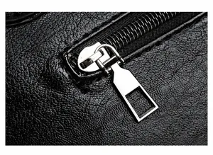 Close-up of smooth metal zipper and premium leather texture on a black shoulder bag