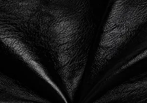 Close-up of premium black faux leather texture with natural grain and soft glossy finish