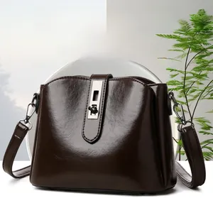 Detailed view of dark brown glossy leather crossbody bag with silver metal clasp closure