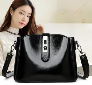 Detail of black glossy faux leather shoulder bag with silver metallic twist lock closure