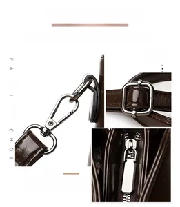 Detailed view of gunmetal hardware turn-lock and adjustable buckle on dark brown leather bag