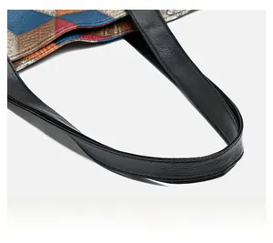 Detailed view of comfortable faux leather handle and colorful patchwork stitching on tote bag