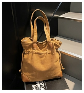Detail of vintage canvas tote bag with brown leather accents on a modern display