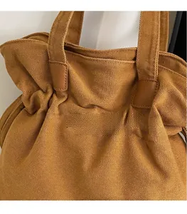 Close-up of caramel canvas tote bag with reinforced leather handles and pleated opening