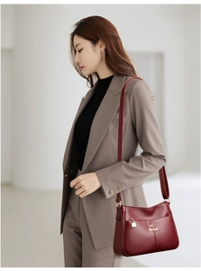 Detail view of burgundy leather handbag with litchi texture and metal kangaroo logo