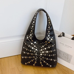 Schwarze Lederbeutel-Tasche im Retro-Stil mit Punk-Nieten auf hellem Holzfußboden