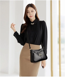 Close-up of black litchi texture leather shoulder bag with gold kangaroo metal logo