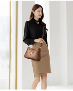 Detail view of brown pebbled leather crossbody bag with golden kangaroo logo and hardware