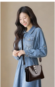 Detail of dark brown polished leather bucket bag with silver clasp on blue denim outfit