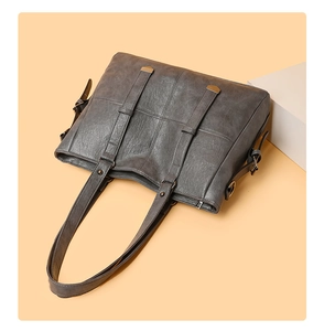 Détail du sac cabas gris montrant la texture du cuir et les boucles métalliques