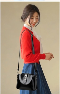 Detail of black glossy leather crossbody bag with metal turn-lock and adjustable strap