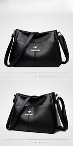 Close-up of black litchi leather texture with golden kangaroo logo on crossbody bag