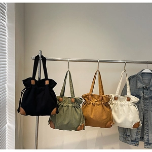 Détail de quatre sacs fourre-tout en toile à cordon en noir, vert, jaune et beige