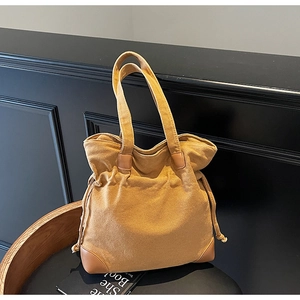 Détail du sac seau en toile jaune montrant les renforts en cuir marron et le cordon de serrage