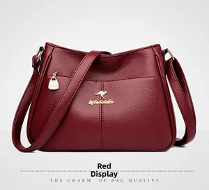 Detailed view of wine red textured leather bag with gold kangaroo logo and zipper