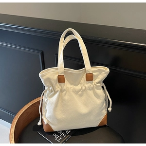 Détail d'un grand sac cabas en toile avec cordon de serrage et renforts en cuir marron