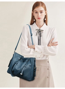 Sac fourre-tout bleu foncé en similicuir huilé porté par un mannequin chic