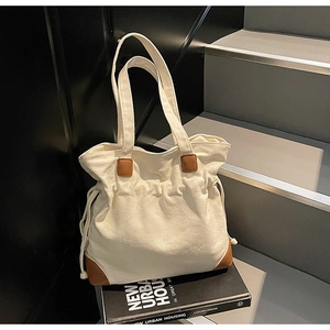Détail du sac fourre-tout crème avec cordon de serrage et renforts en cuir marron aux coins