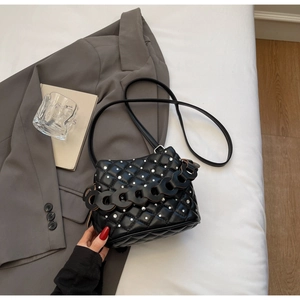 Detail of black quilted crossbody bag with silver stud accents and decorative chain