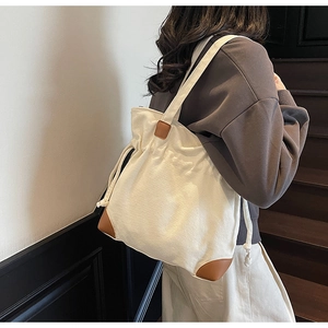 Detail of cream canvas drawstring tote bag with brown leather patches on a model