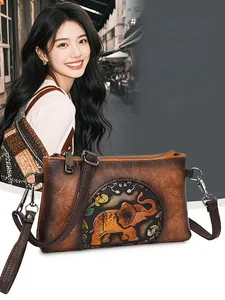 Detail of vintage brown leather handbag with embossed elephant pattern and adjustable strap
