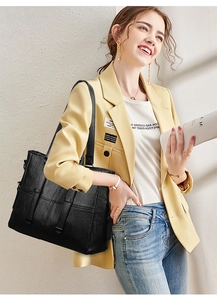 Détail d'un sac cabas en cuir noir avec trois sangles à boucle et texture grainée
