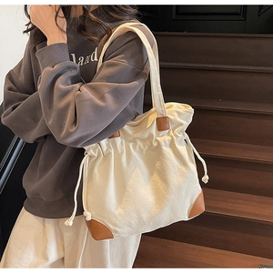 Détail d'un grand sac fourre-tout en toile crème avec coins en cuir marron et cordon serrage