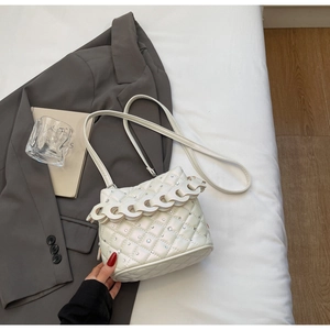 Macro detail of white quilted bucket bag with shimmering rhinestones and wavy chain
