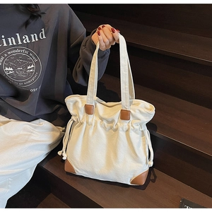 Détail du grand sac cabas en toile avec garniture en cuir marron et cordon de serrage latéral