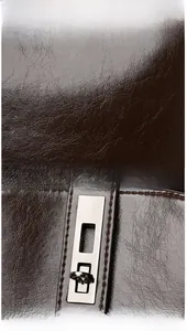 Detail of dark brown lychee leather texture and silver rectangular twist lock on bag