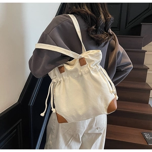 Détail d'un sac seau en nylon crème avec des accents en cuir marron sur modèle