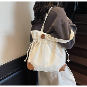 Détail du sac seau en nylon beige minimaliste avec garniture en cuir brun et cordon