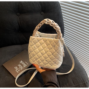 Detail showing the white quilted bucket bag with rhinestones on a black corduroy seat