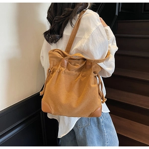 Detail view of large canvas drawstring tote bag with leather trim on model