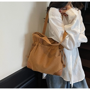 Detailed view of caramel canvas tote bag showing drawstring closure and leather reinforcement